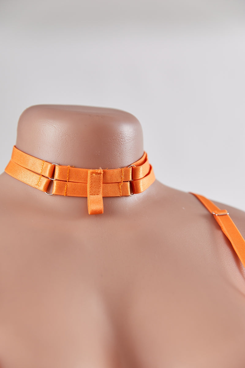 Mannequin wearing an orange choker and top against a plain background