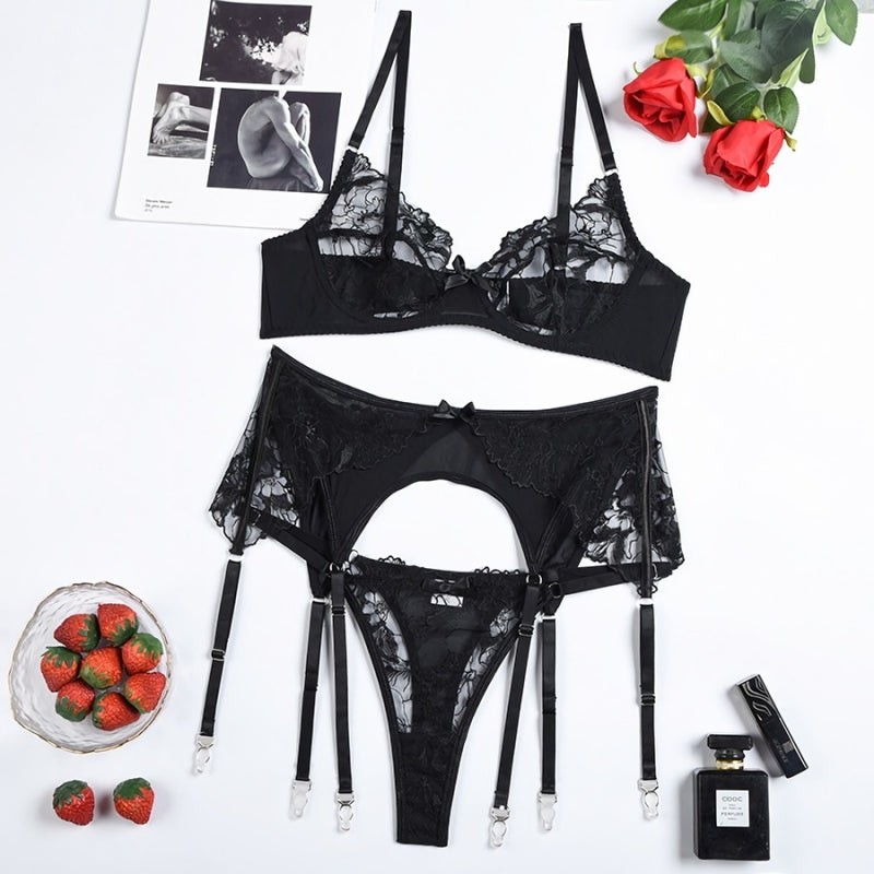 Black lace lingerie set with garters on a white background with decorative items.